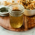 A jar of calendula oil and a bowl of dried calendula flowers.