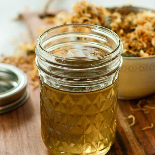 A jar of calendula oil on a wooden board.