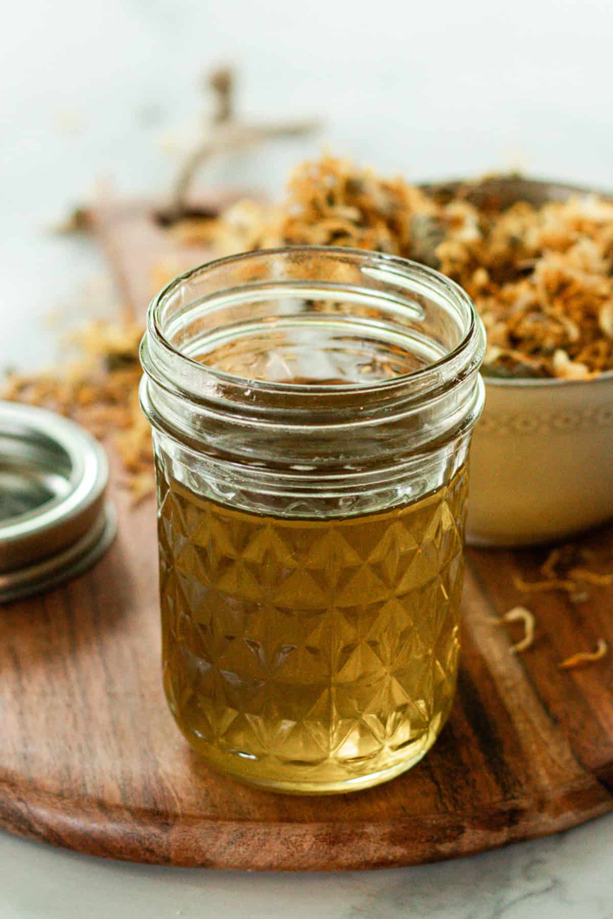 A jar of calendula oil on a wooden board.