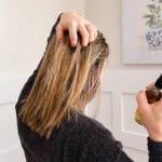 Holding my hair apart as I spray rosemary water onto the strands.