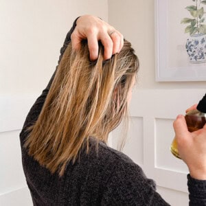 Holding my hair apart as I spray rosemary water onto the strands.