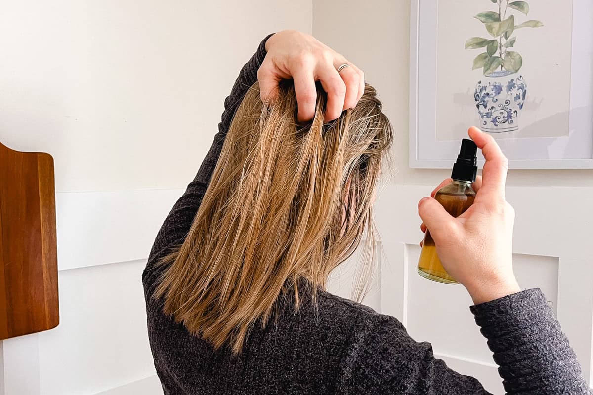 Spraying the rosemary water into the strands of my hair. 