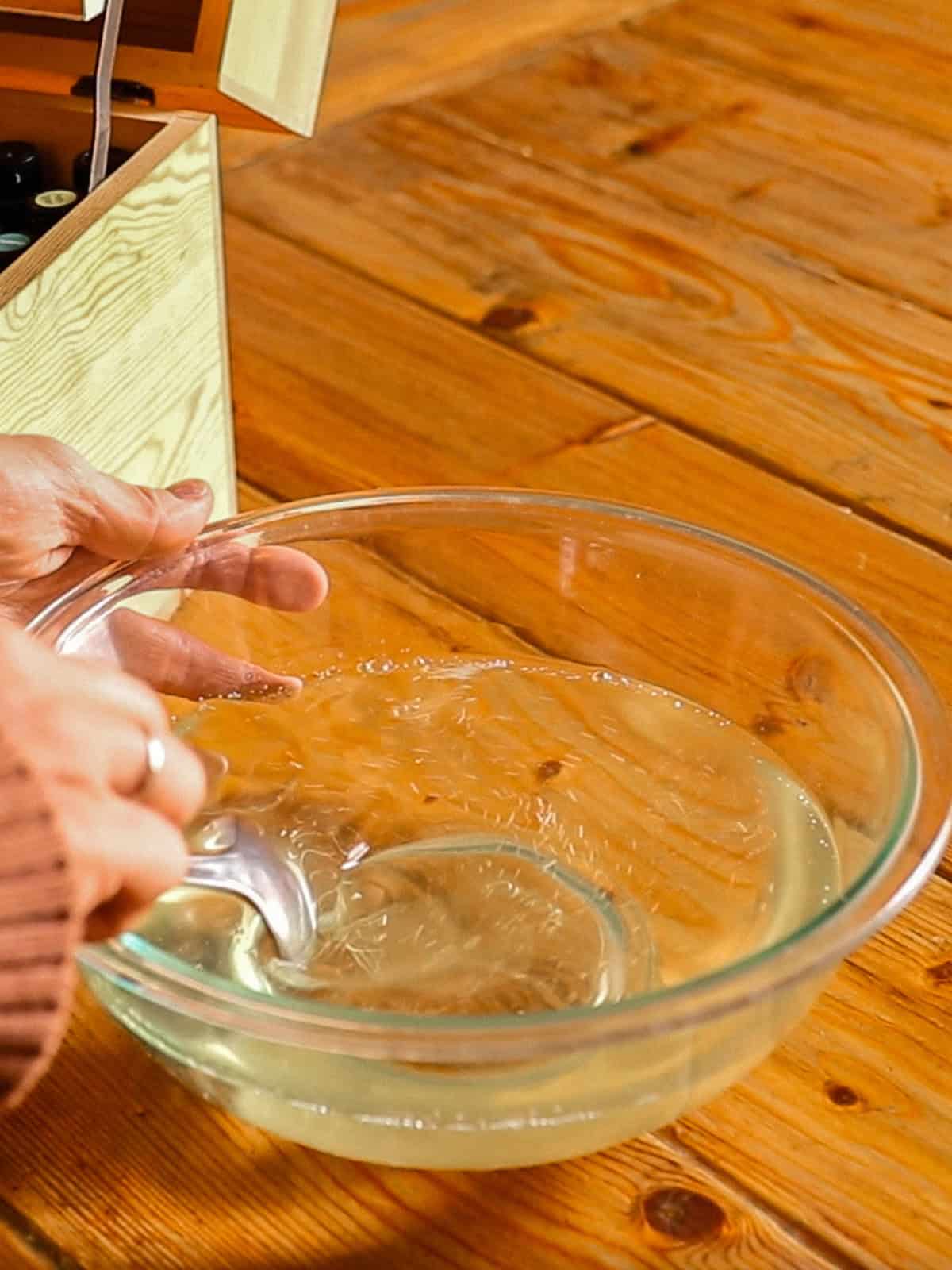 Stirring melted oils together in a glass bowl.
