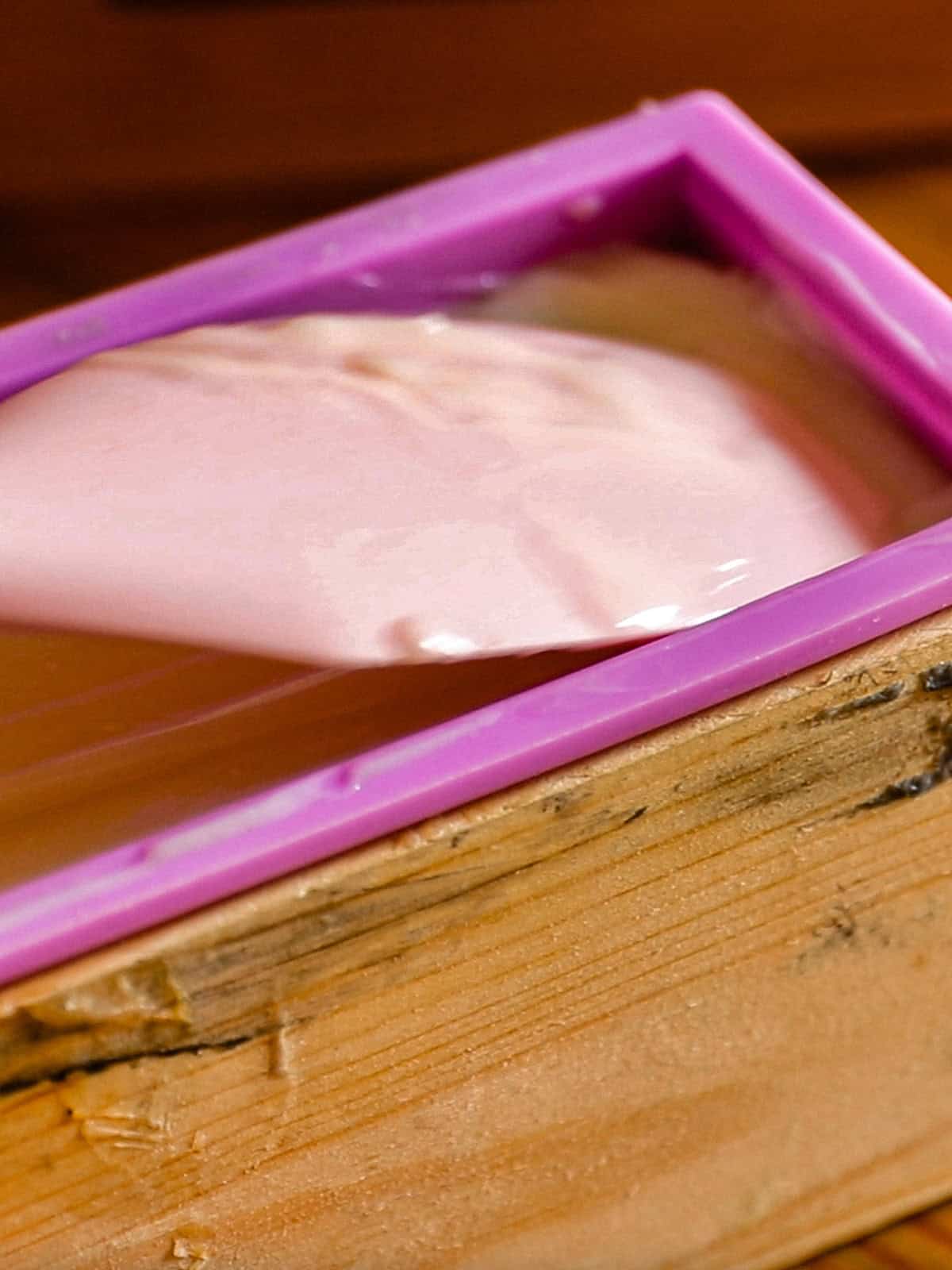 Spreading soap mixture into a loaf mold.