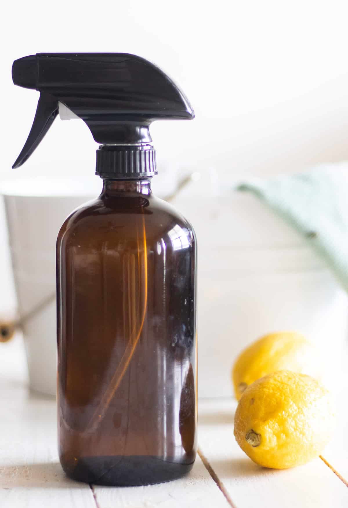 A bottle of all purpose cleaner next to a lemons and a cleaning bucket.