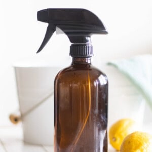 A bottle of all purpose cleaner with a bucket and rag behind it.