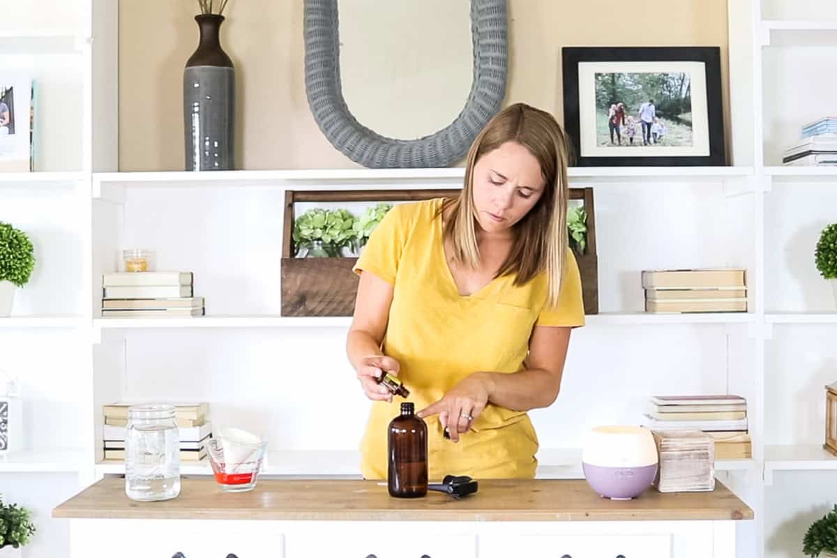 Adding essential oils to a spray bottle. 