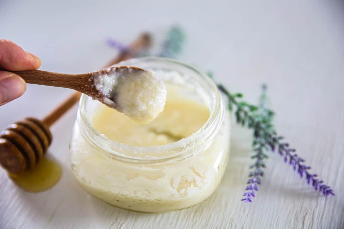 Scooping a spoonful of homemade face wash out of a jar.