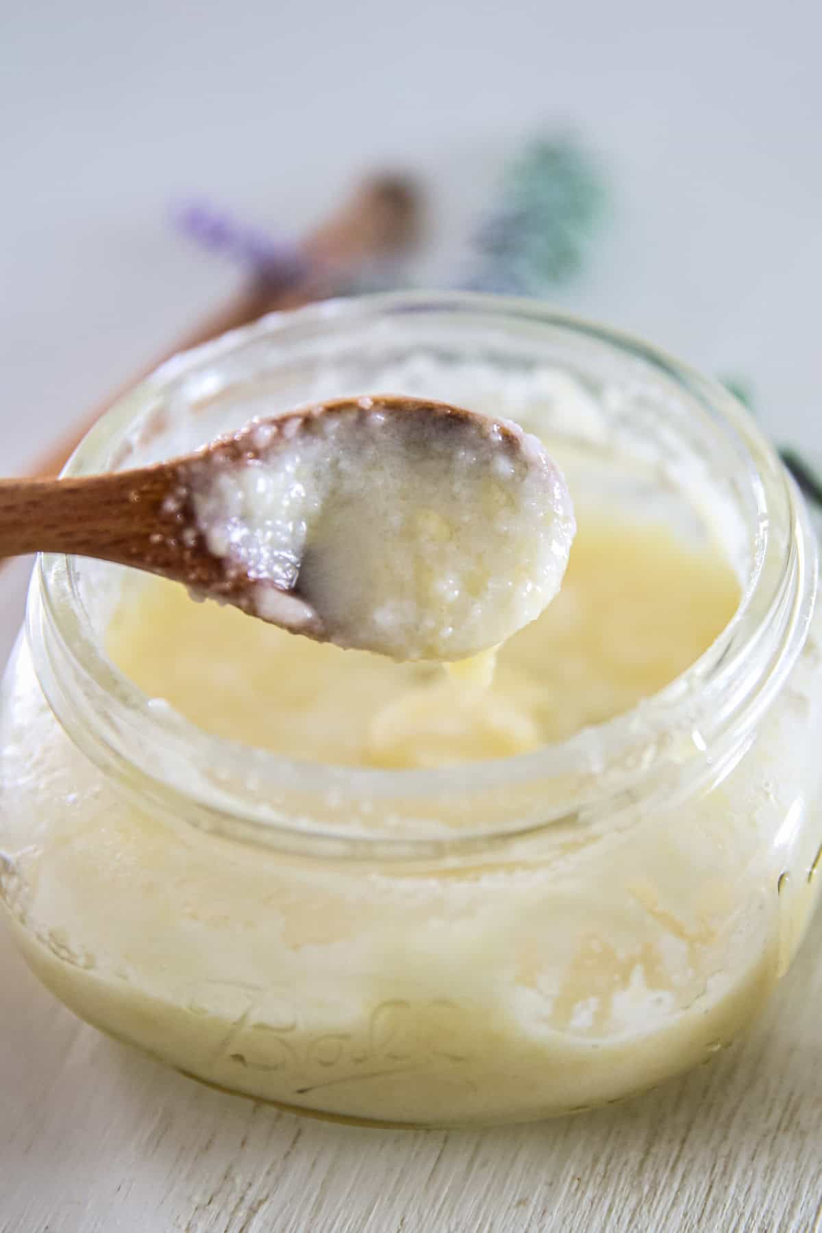 A spoonful of DIY face wash held over a jar of face wash.