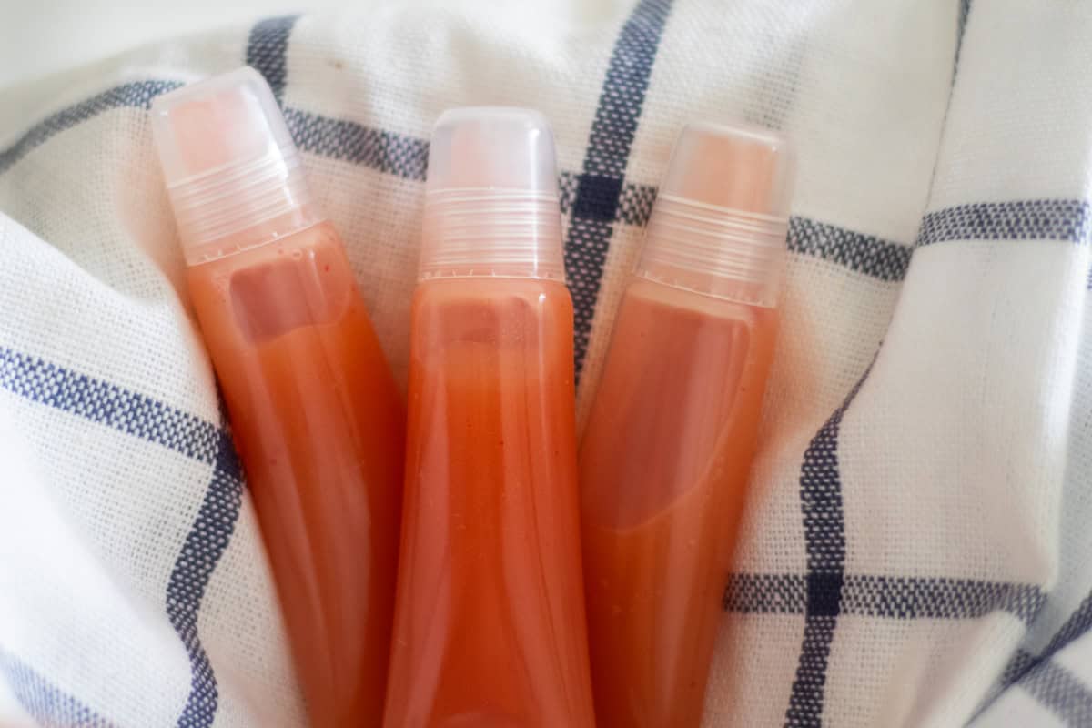 Three tubes of DIY lip gloss on a white and blue towel.