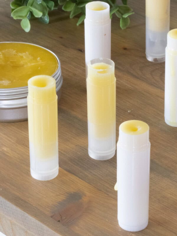 Several tubes of homemade anti itch cream sitting on a wooden table while the ingredients harden.