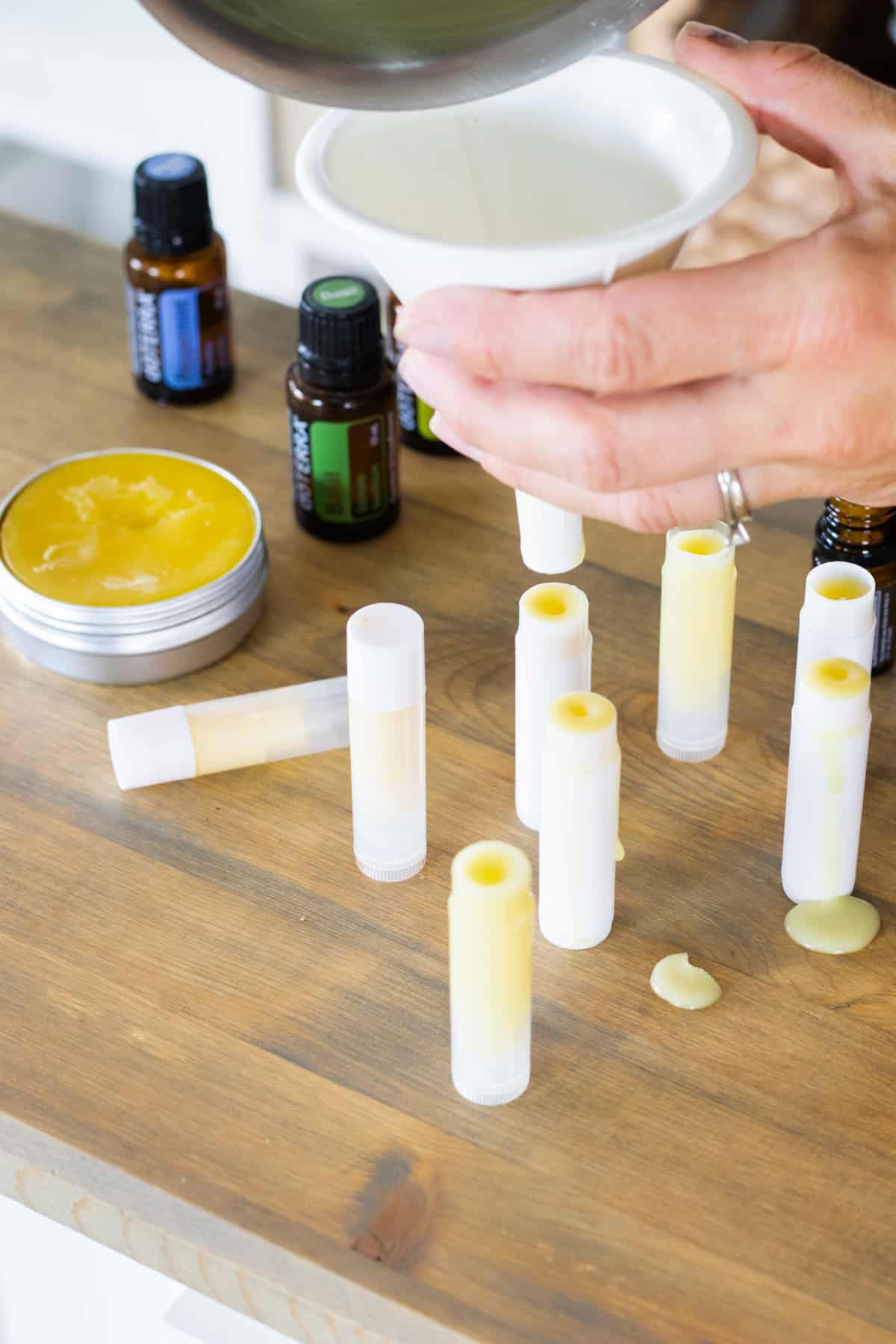 Using a funnel to pour the melted cream into old lip balm tubes.