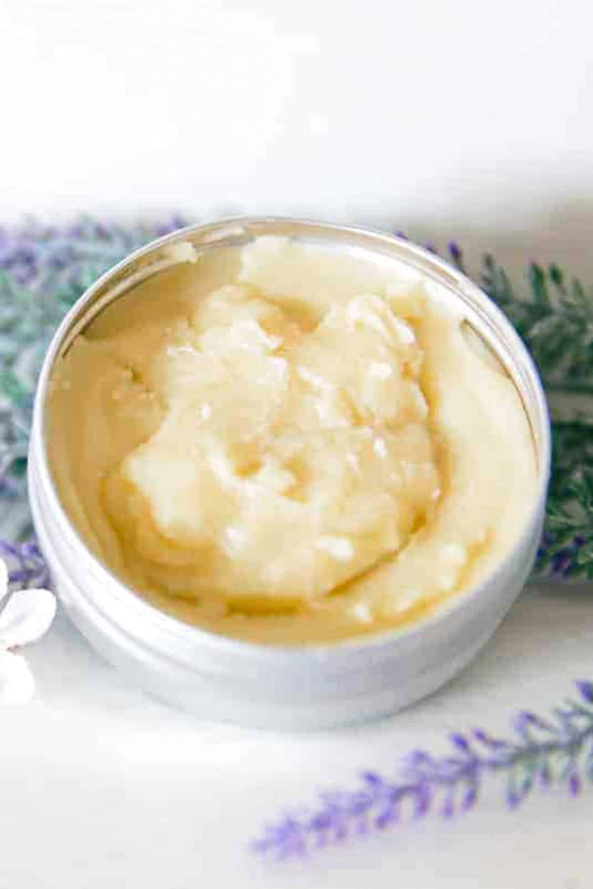 A small tin of homemade skin salve on a white vanity. 