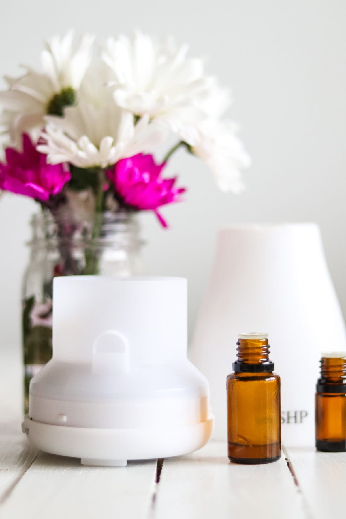 A diffuser with bottles of essential oils and fresh flowers.