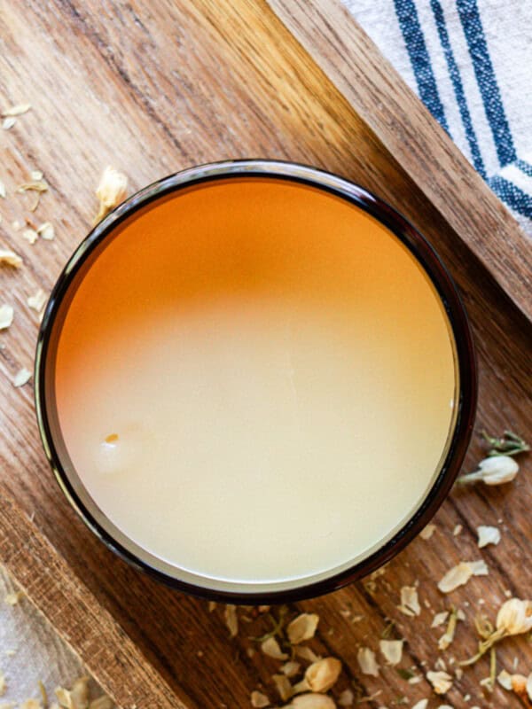 Homemade tallow balm in an amber jar on a wooden board.