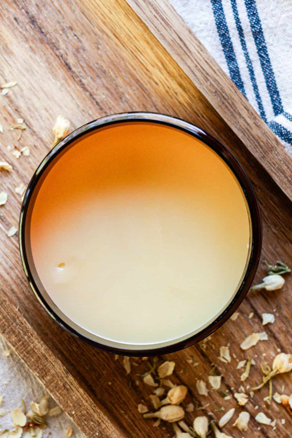 Homemade tallow balm in an amber jar on a wooden board.