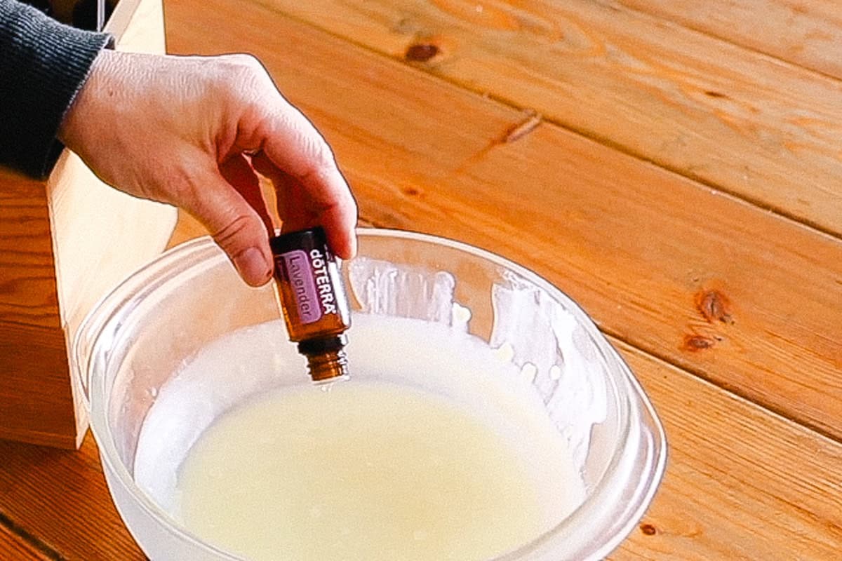 Dropping essential oils into a bowl of tallow balm.
