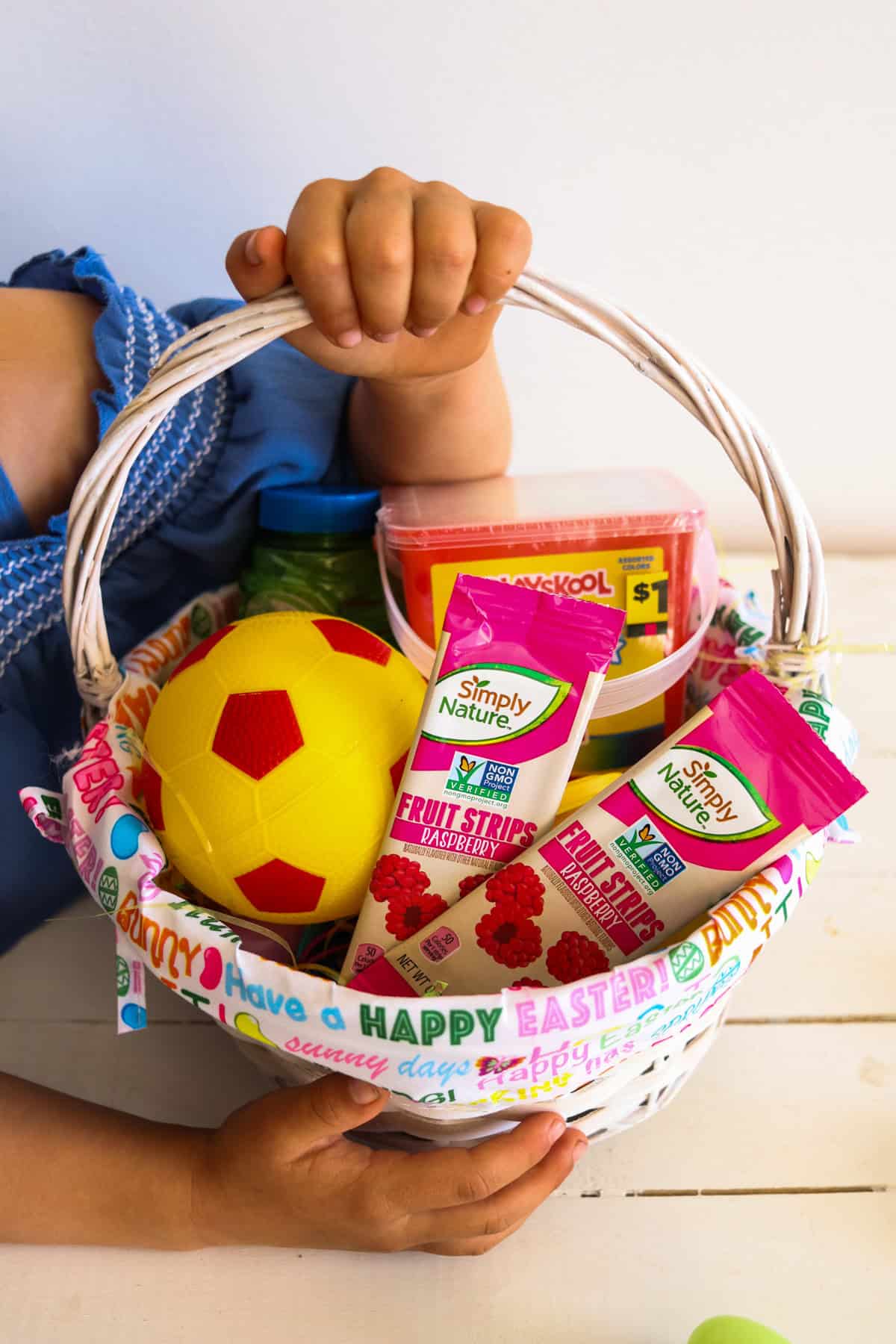 A little hand holding an easter basket filled with non-candy treats.