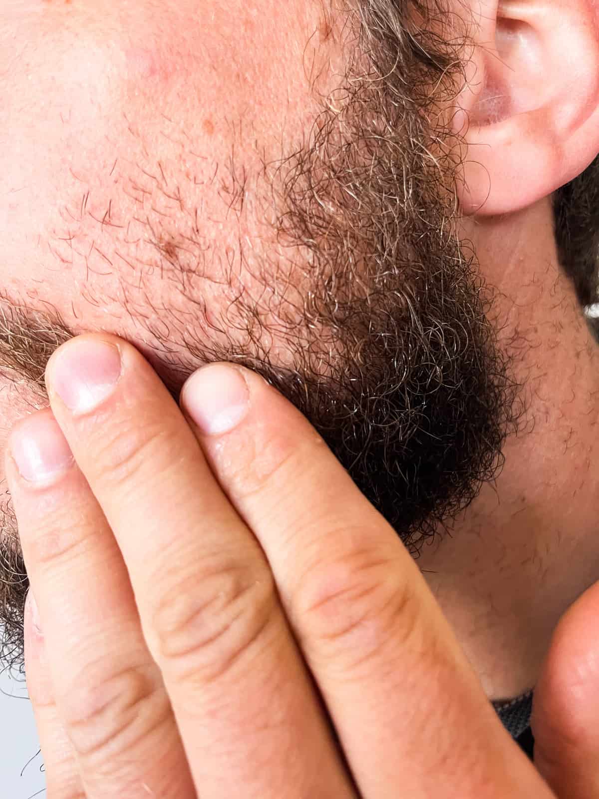 Rubbing beard oil into a beard.