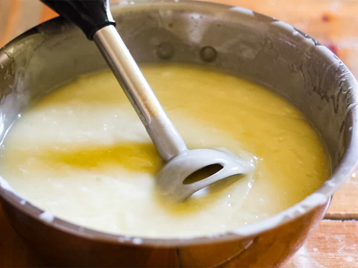 An immersion blender in a bowl of soap, after reaching trace.