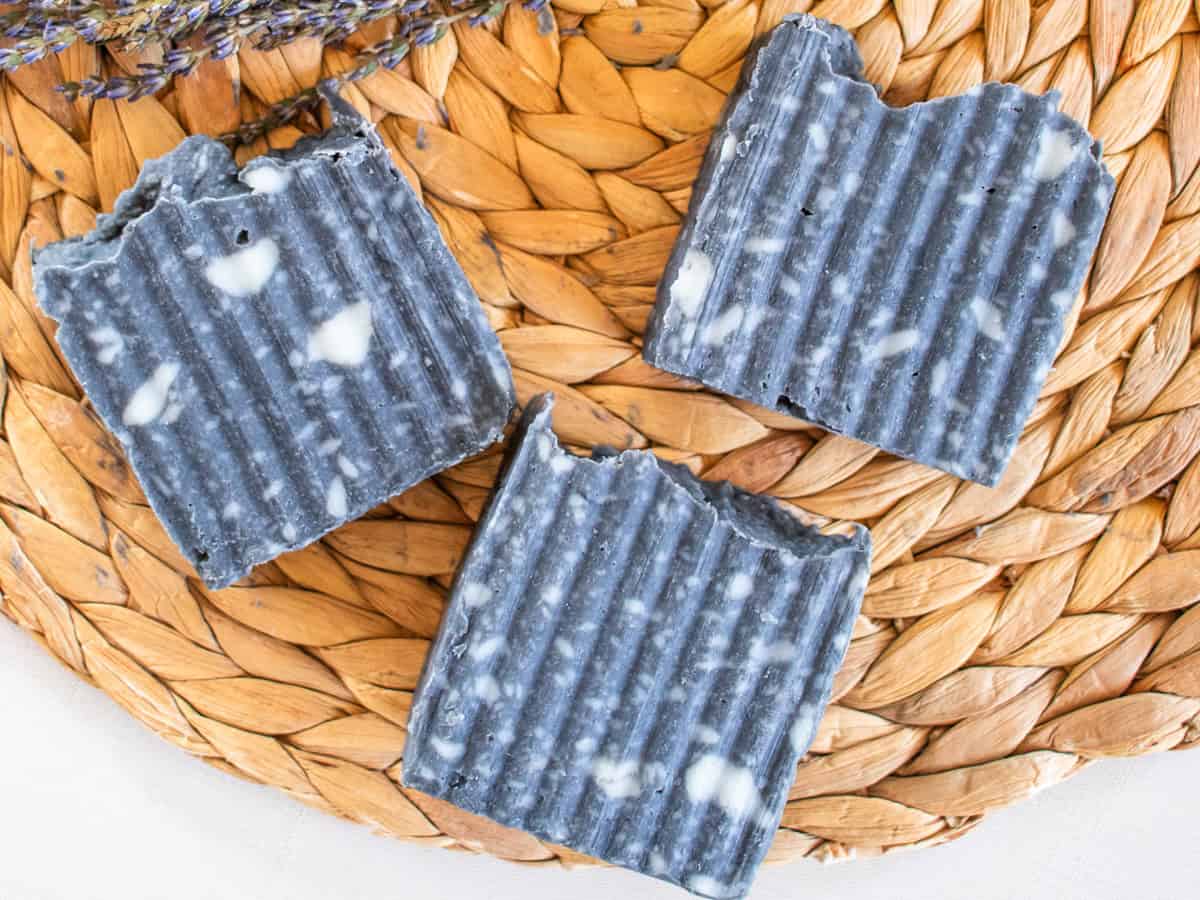 Three bars of charcoal soap on a wicker placemat.