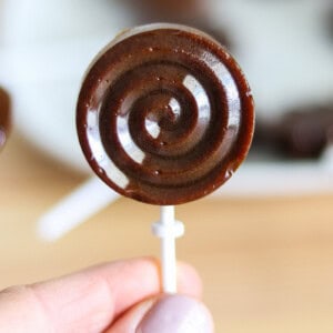 Homemade lollipop being held above a plate of lollipops.