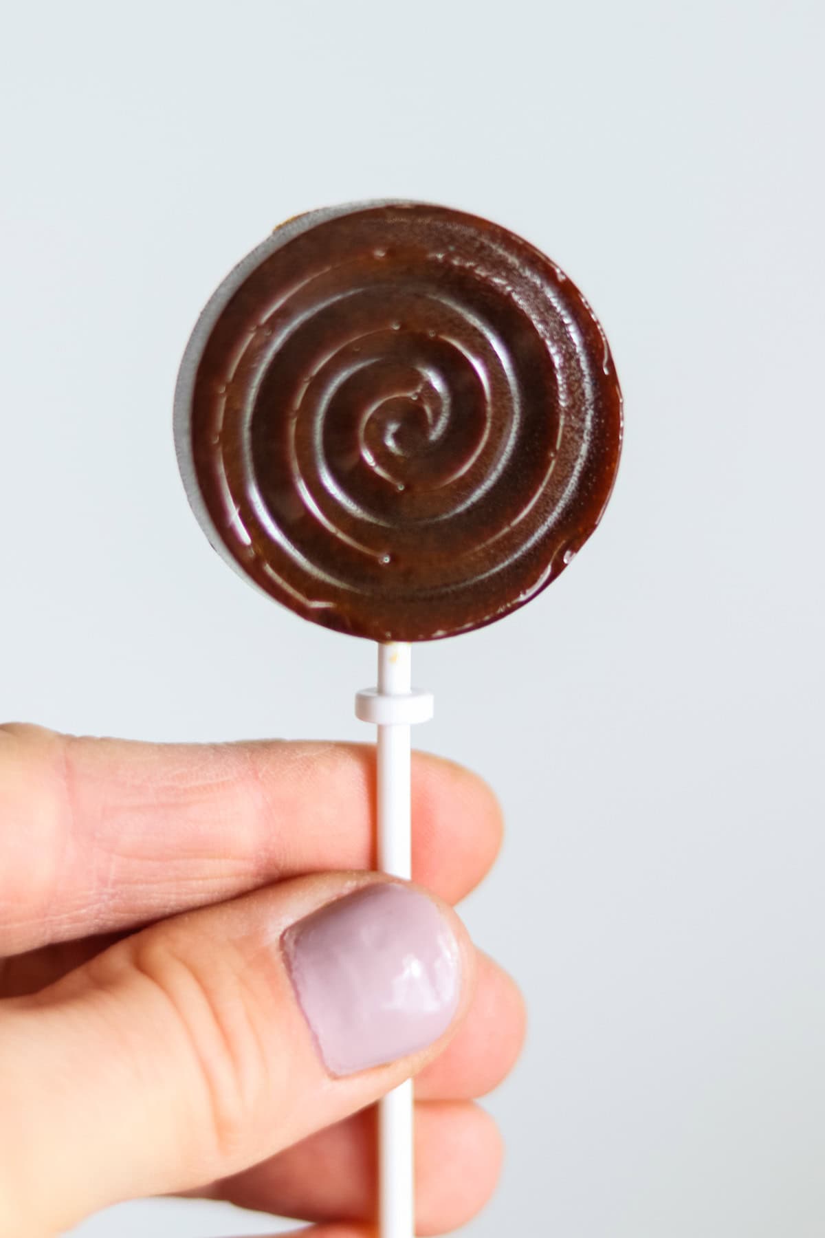 Holding a healthy homemade lollipop up in the air.