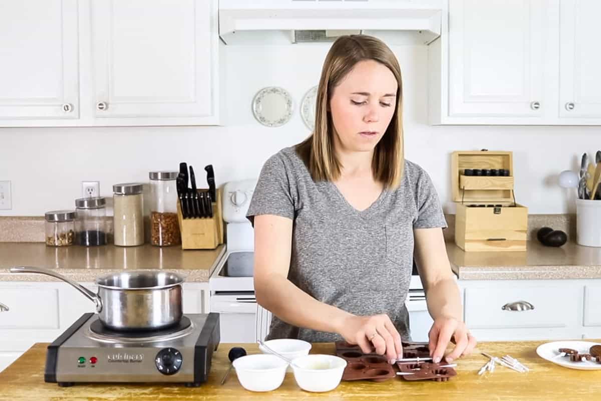 Placing lollipop sticks in sucker molds.