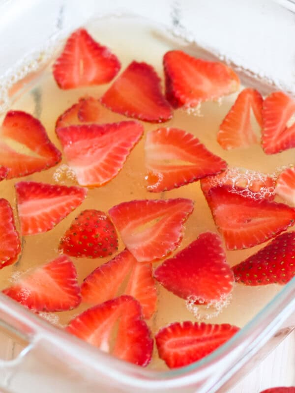 Sugar free jello in a glass dish with sliced strawberries in it.