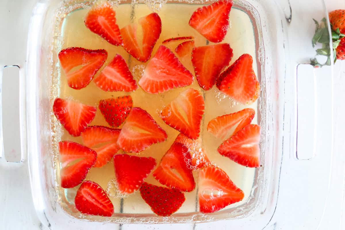 A baking dish of sugar free jello with sliced strawberries.