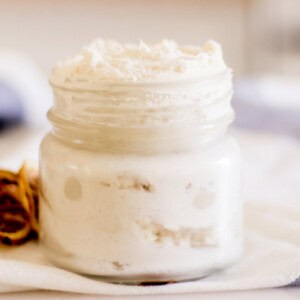 A small jar of homemade hand cream on a white and blue towel.