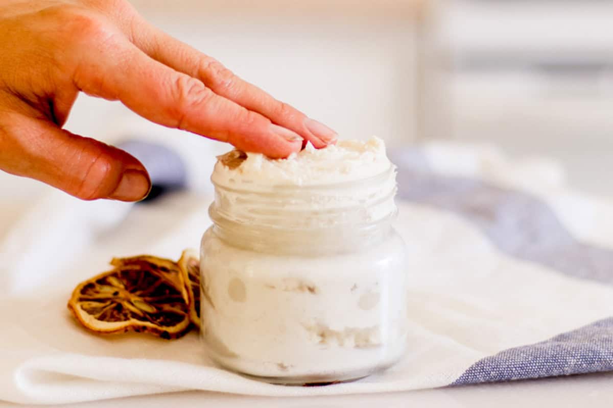 Using fingertips to get a little hand cream out of the airtight container. 