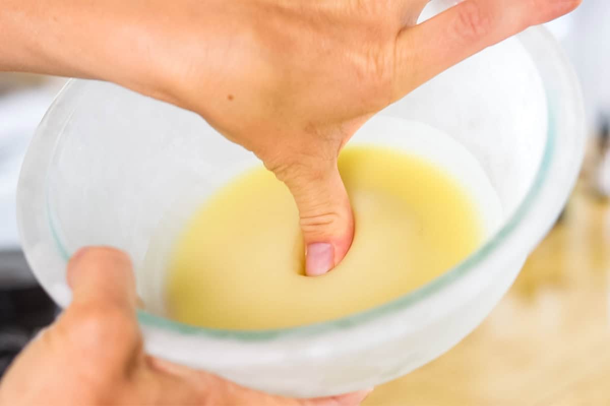 Pressing a thumb into the  cream to test the firmness of it. 