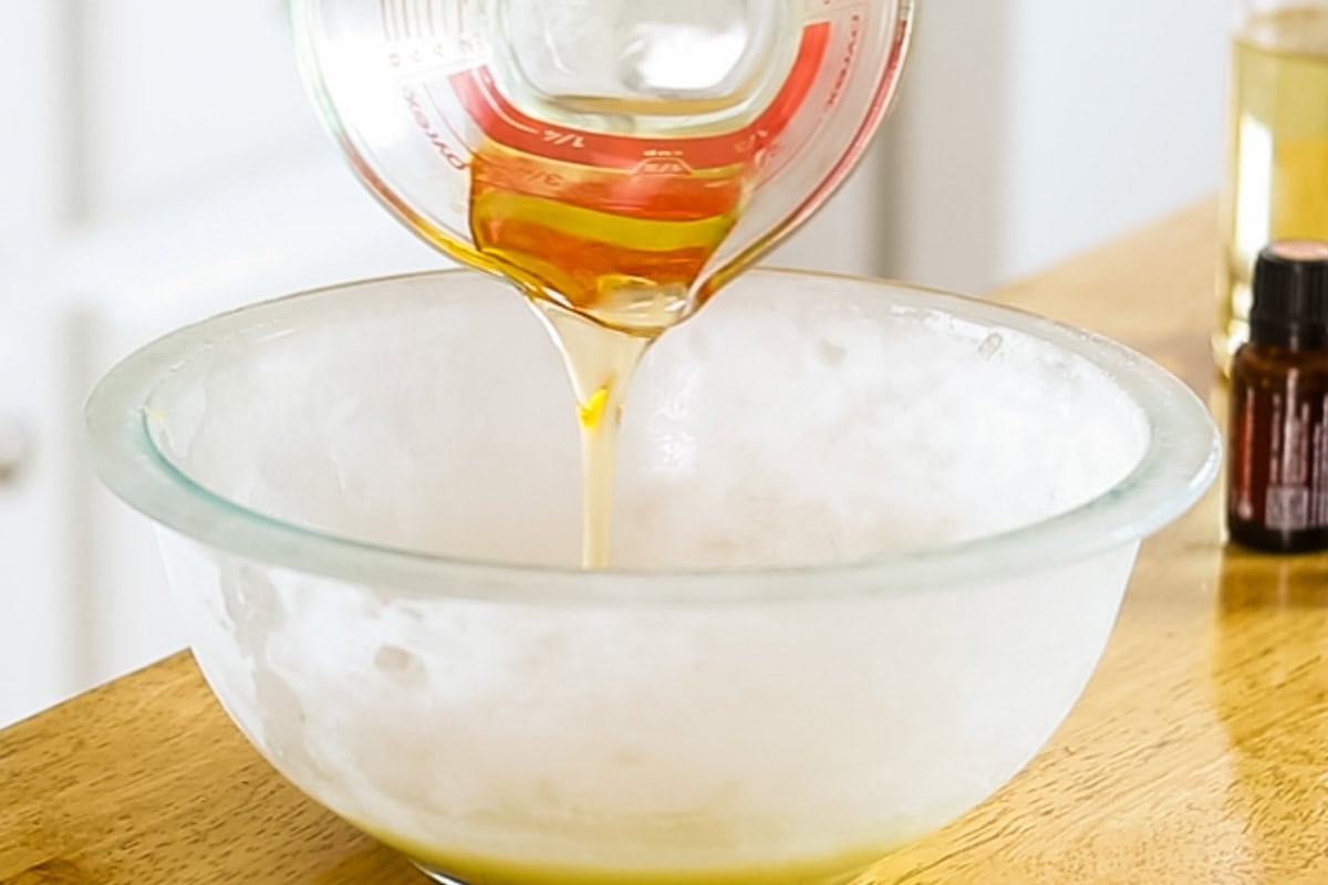 Pouring the jojoba oil and vitamin E oil in to the double boiler with the butters.