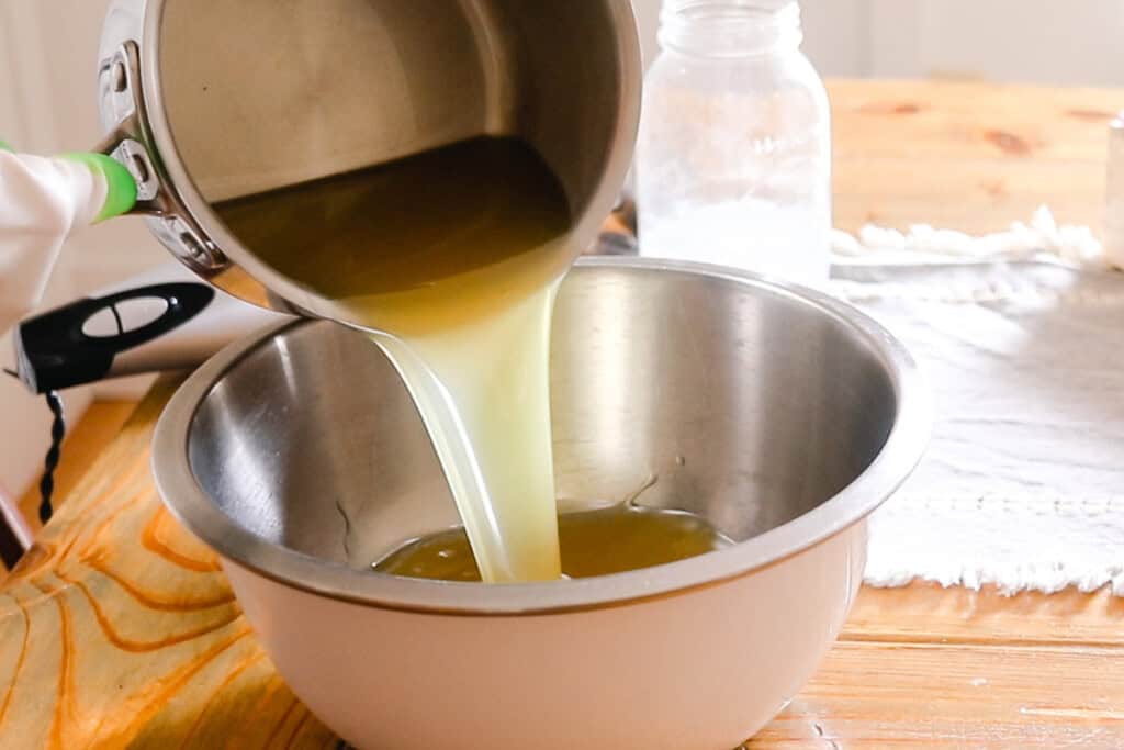 Pouring melted oils into a metal bowl.