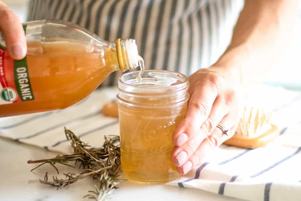 Pouring apple cider vinegar into a mason jar. 