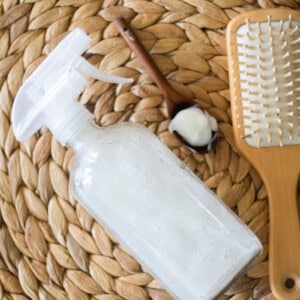 Hair heat protectant spray with a hair brush on a wicker placemat.