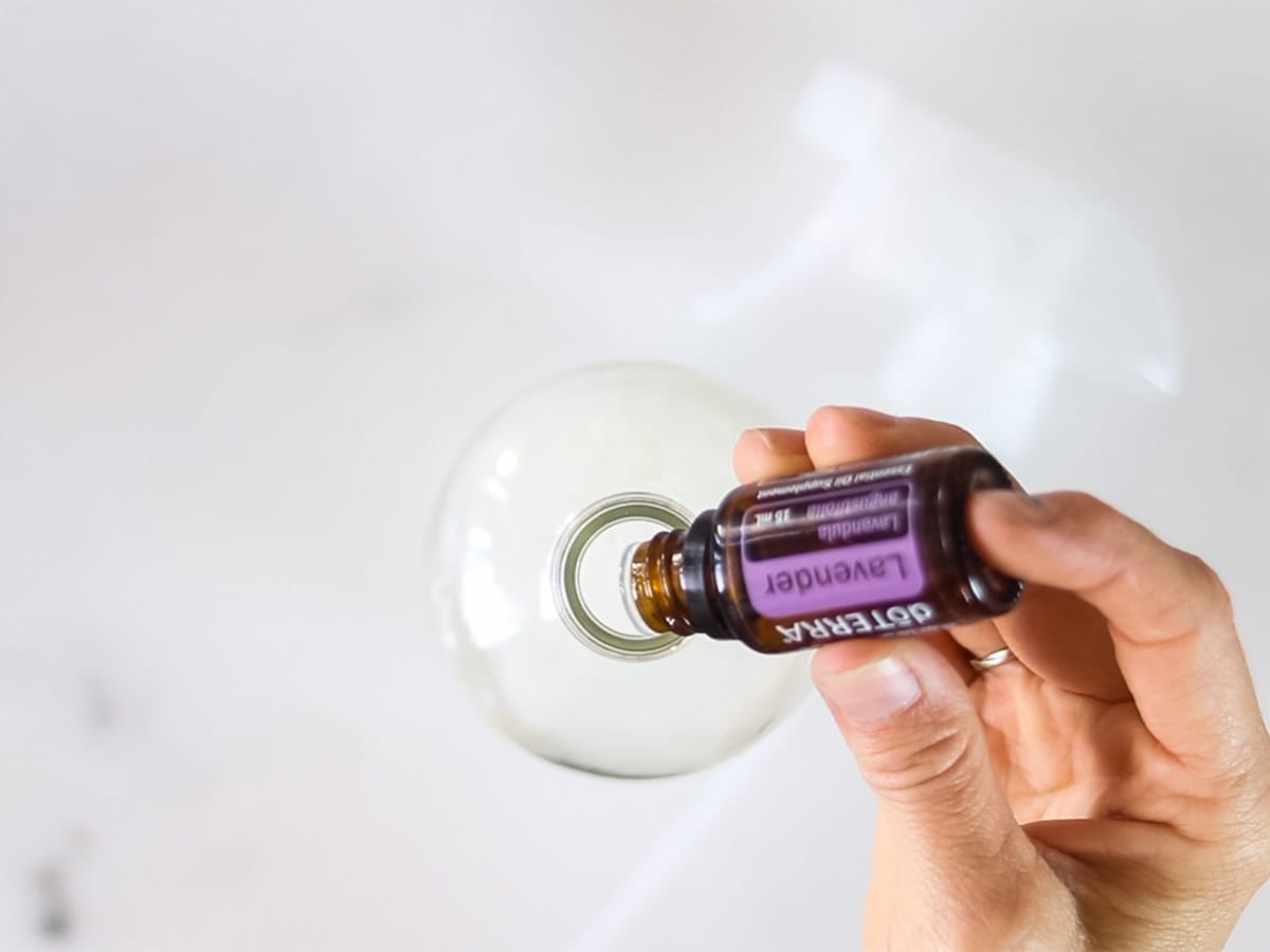 Dropping lavender essential oil into a spray bottle. 