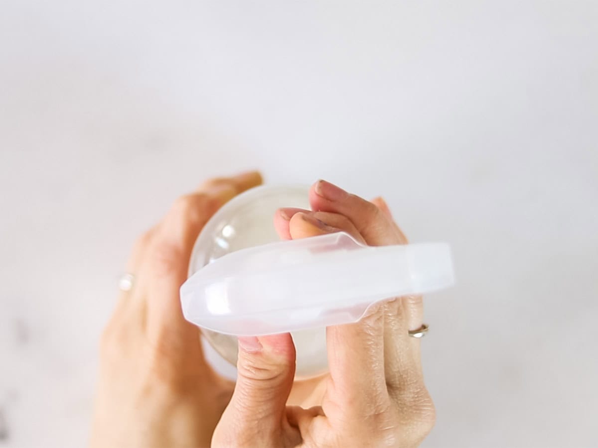 Tightening a lid on a spray bottle of hair heat protectant. 