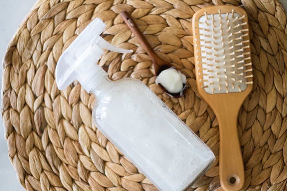 Hair heat protectant spray with a hair brush on a wicker placemat.