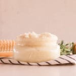 A jar of homemade protein hair mask with a hair brush on a striped towel.