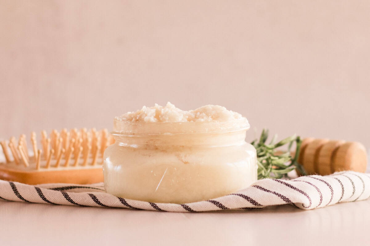 A jar of homemade protein hair mask with a hair brush on a striped towel.