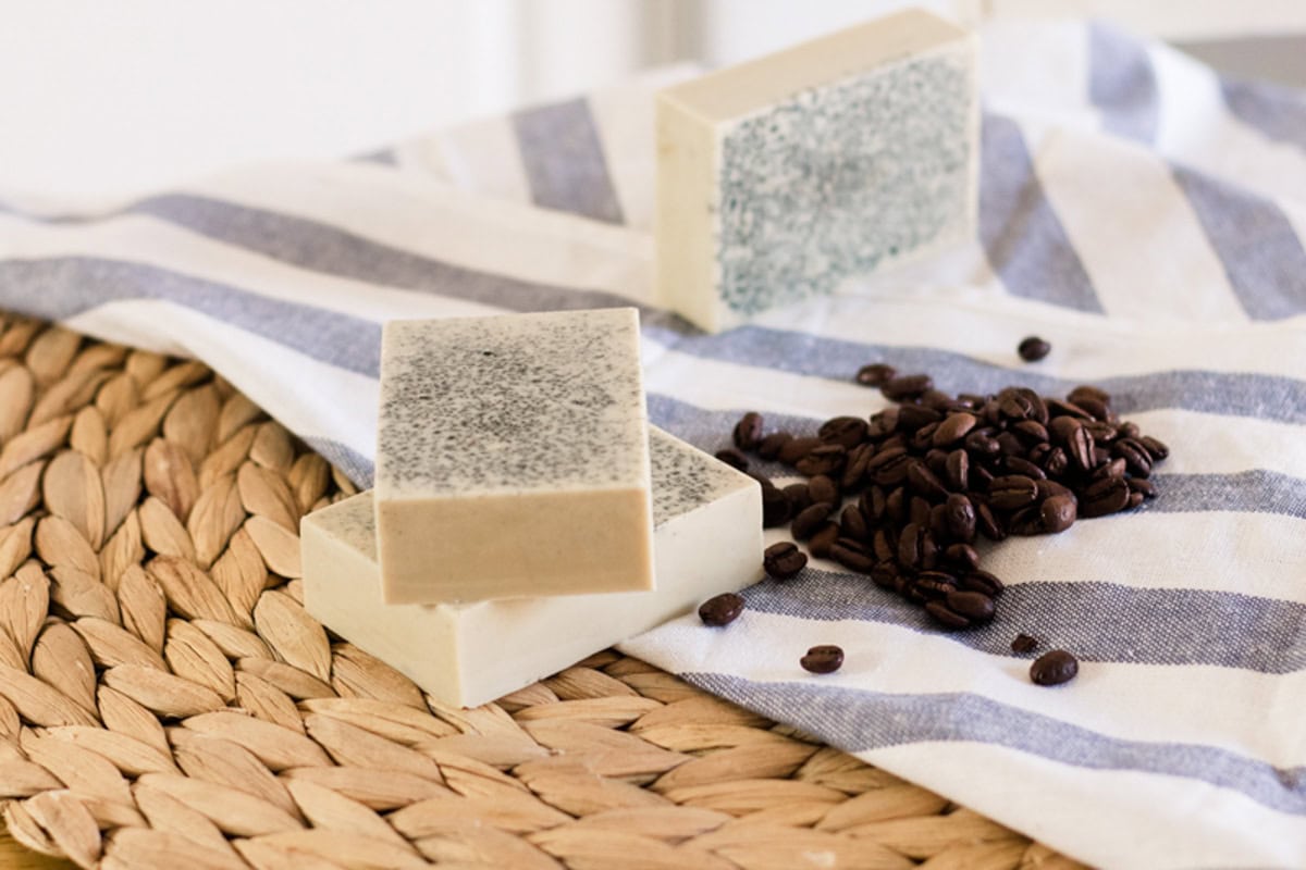 Goat milk soap bars on a wicker placemat with a blue striped towel.