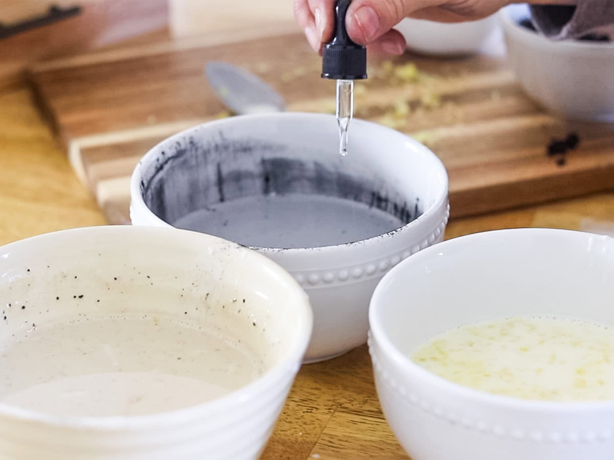 Adding drops of essential oils to a bowl of melted soap base.