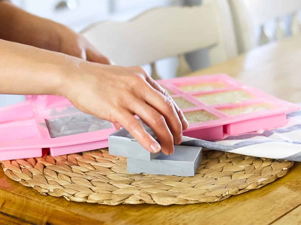 Pulling bars of soap out of a pink silicone soap mold.