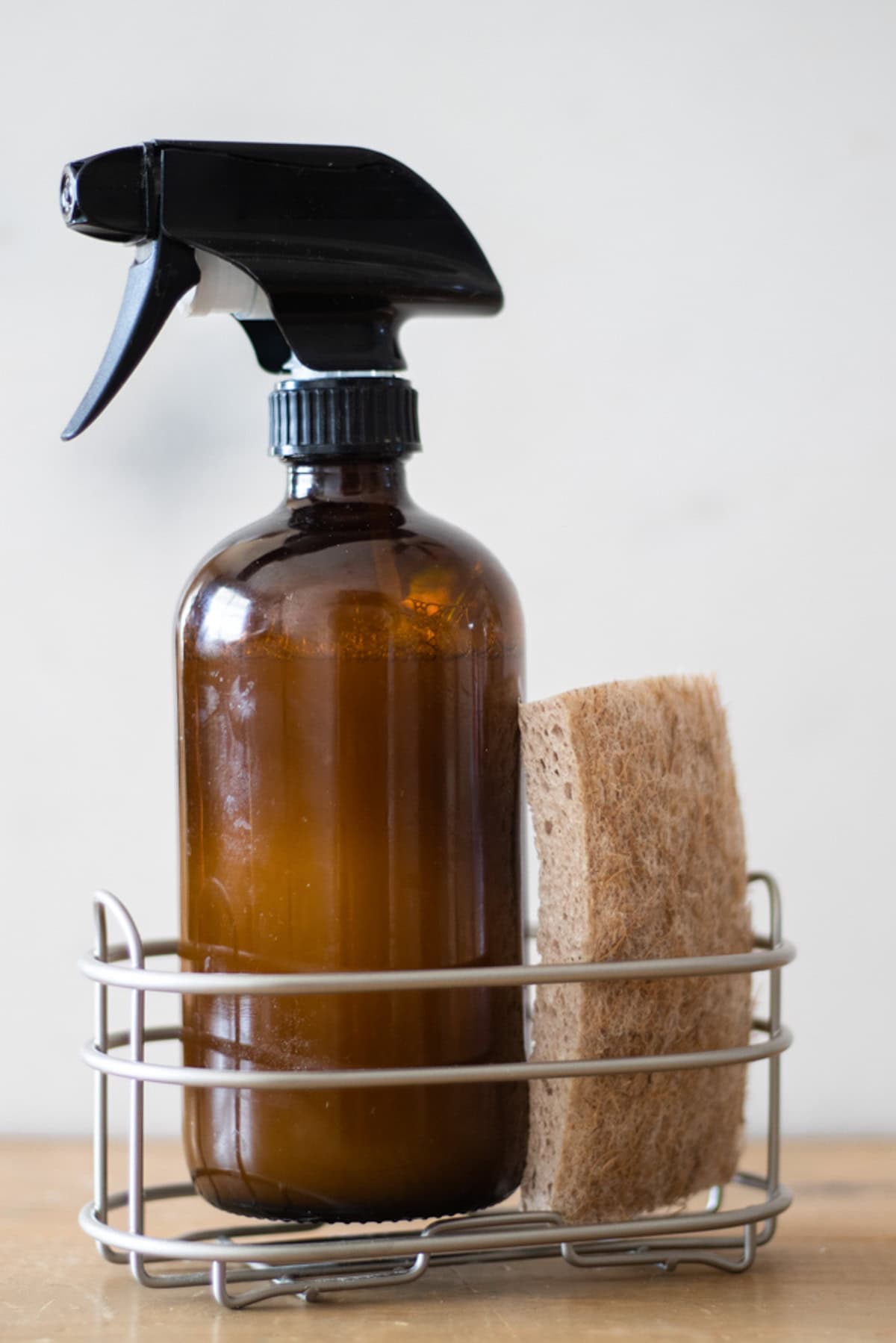 Homemade granite cleaner in a wire basket with a sponge.