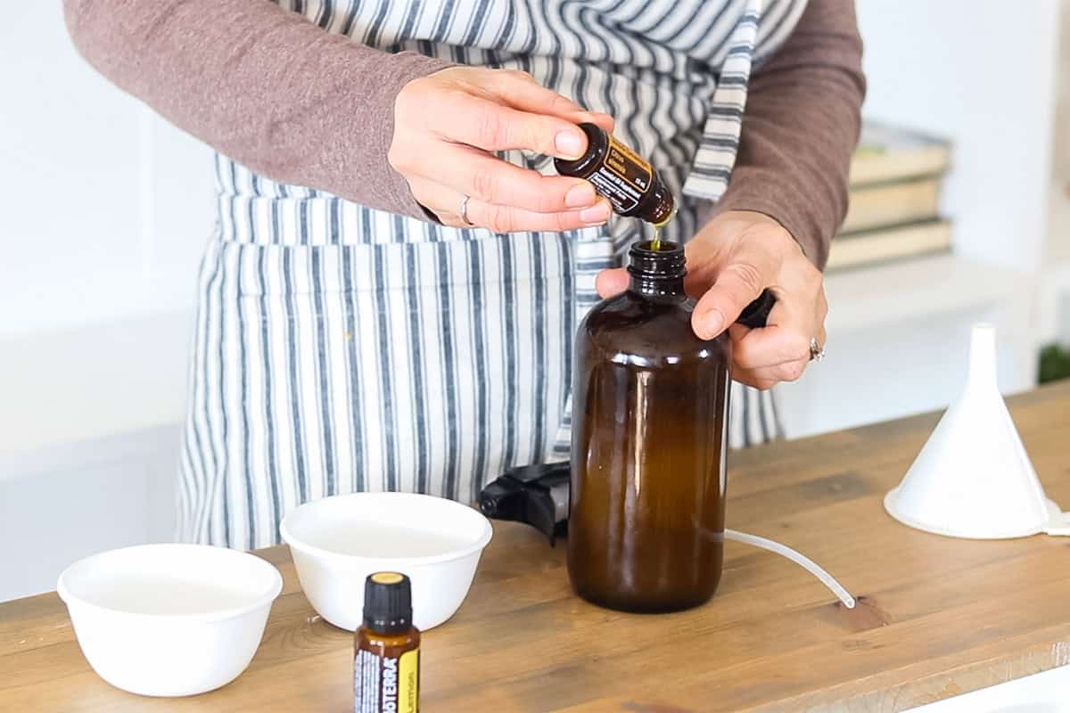 Dropping essential oil into a glass spray bottle.