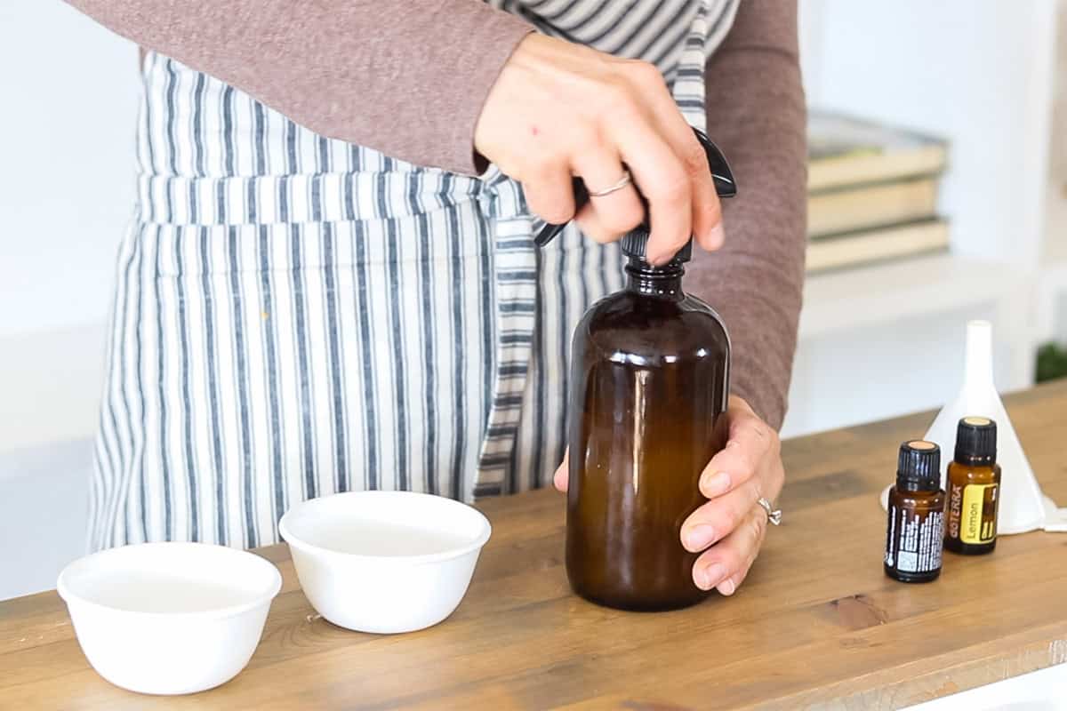 Tightening the lid on an amber glass spray bottle.