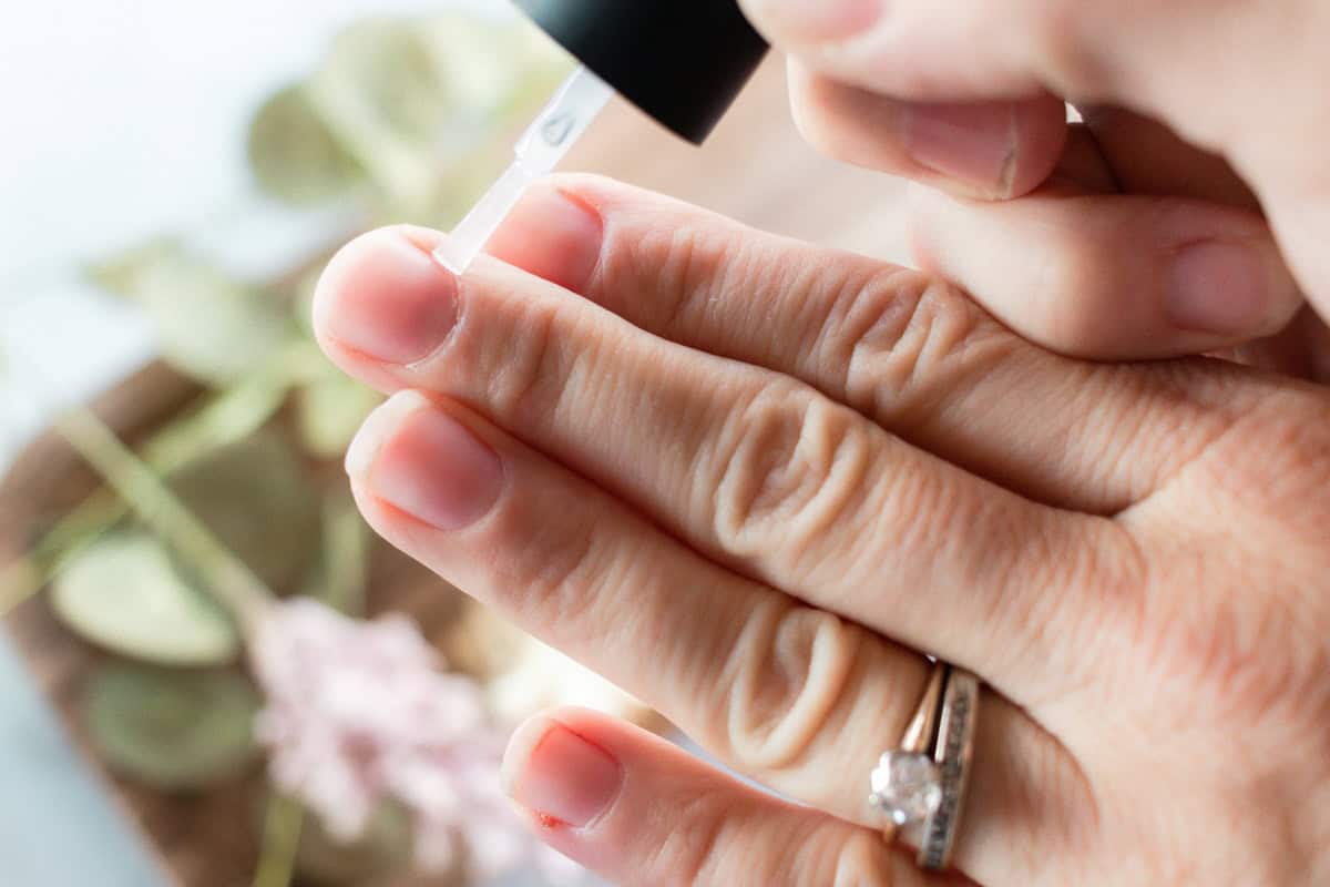 Brushing cuticle oil onto the nail beds.