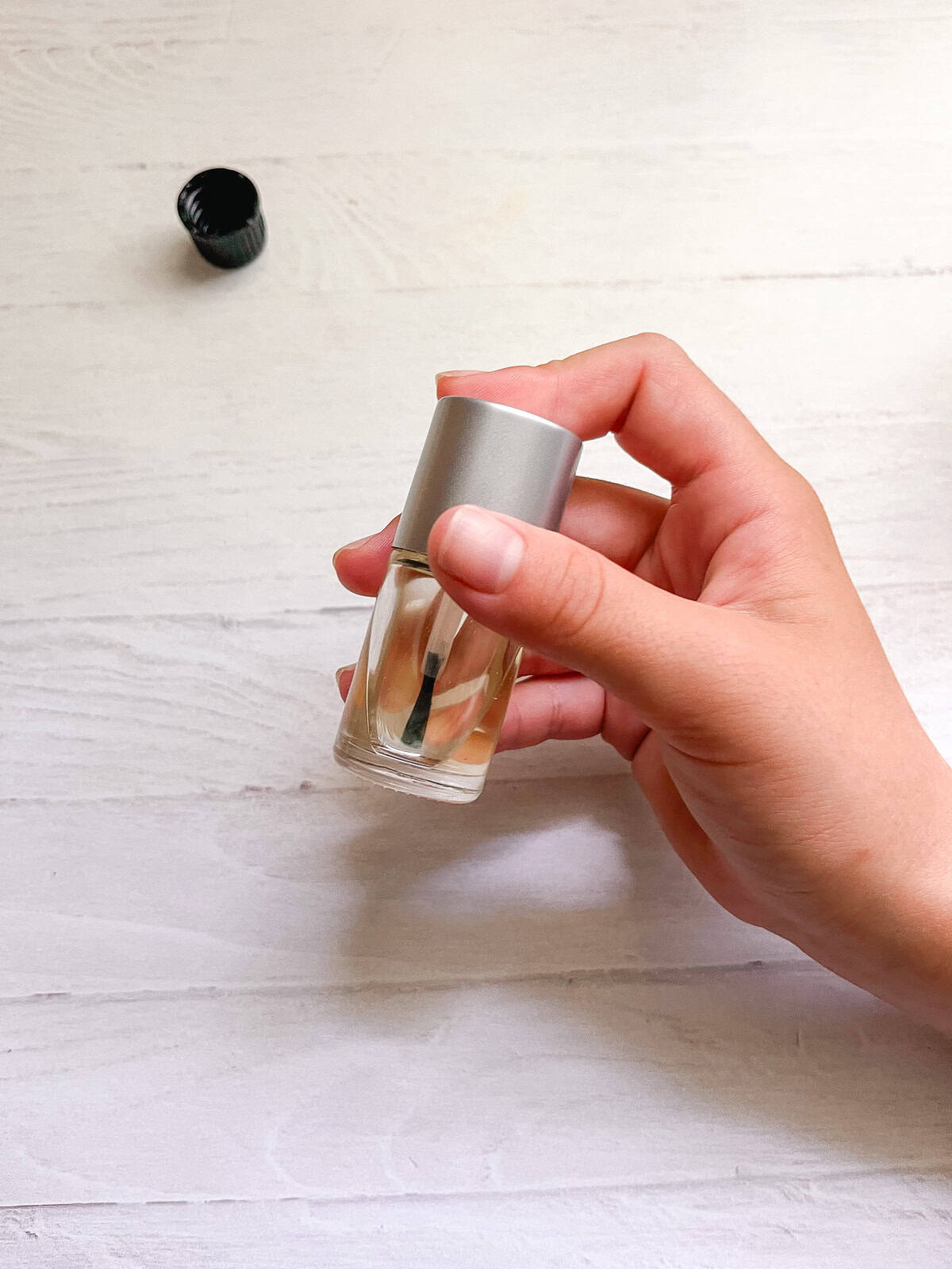 Shaking a bottle of cuticle oil to mix it up. 